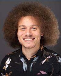 Christofer is looking at the camera and smiling with a black shirt on.