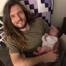 Travis Parker holds a newborn baby.